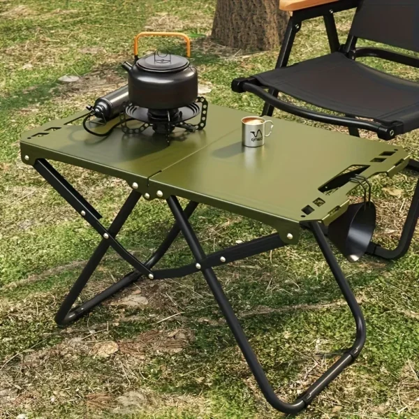 Stainless steel camping table folded open at a beach campsite with plates and drinks