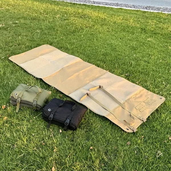 Army green foldable tactical gear mat laid out on grass with camping gear on top