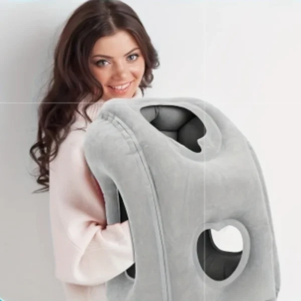 Inflatable travel pillow in light grey with adjustable valve resting on a sleeping bag