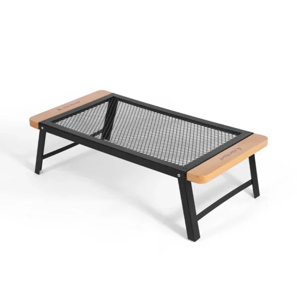 Folding campfire grill table with black steel grate standing over a campfire with a pot on top