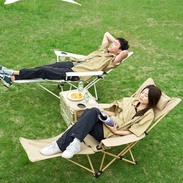 Reclining camping chair with footrest extended and pillow headrest set up on a sandy beach