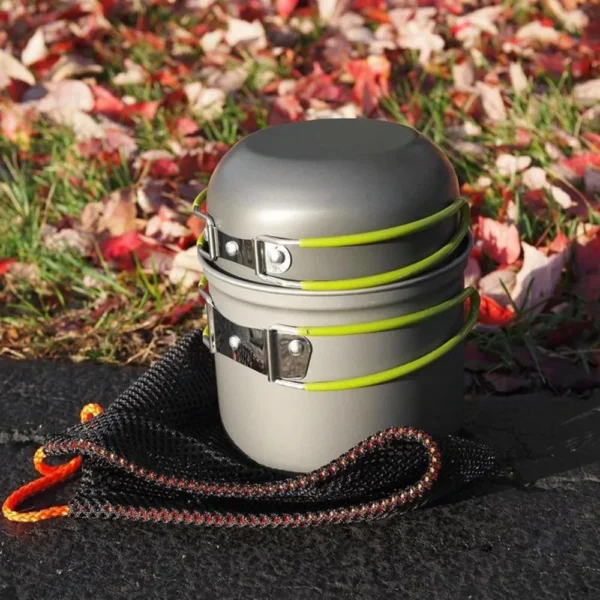 2L camping pot set with green aluminum pot, cover and storage net bag on a forest log