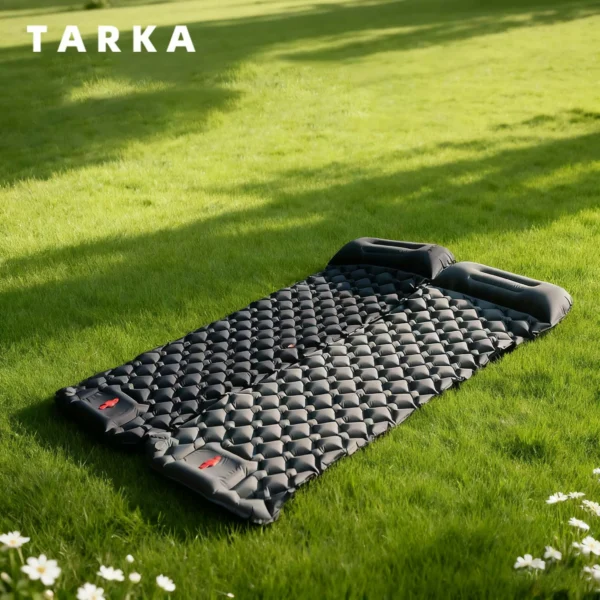 Army green inflatable camping mat with pillow attached at one end laid out on a tent floor
