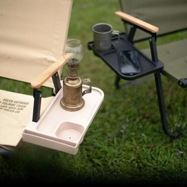 Khaki camping chair side tray clipped to a folding chair armrest holding a cup and a smartphone