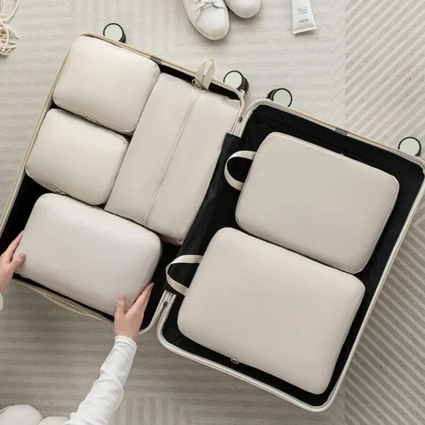 Grey 6 piece packing cubes set with matching handbag laid out beside a suitcase