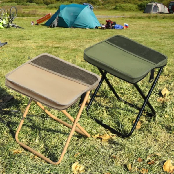 Collapsible shoulder bag stool in green unfolded on a riverbank beside fishing gear