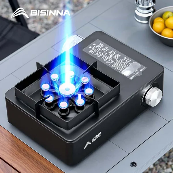 Black high power gas burner with 9 cores lit under a pot on a camping table