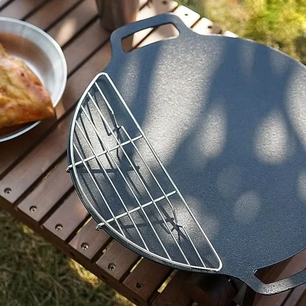 Stainless steel steam rack inside a camp frying pan holding grilled meat over a stove