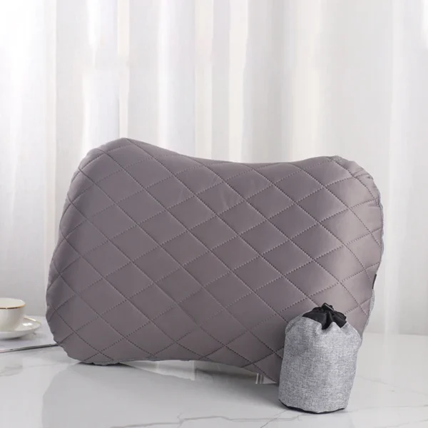 Inflatable headrest pillow in orange used as a cushion on a beach chair near a tent