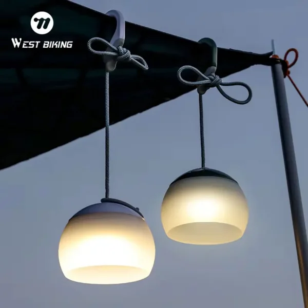 Hanging tent light in olive green glowing from the ceiling loop of a camping tent