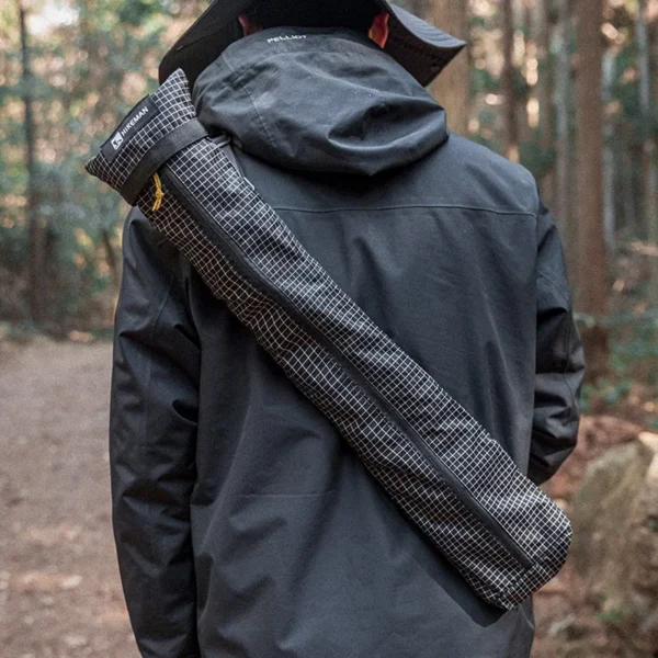 Black nylon trekking pole storage bag with sling strap holding a pair of folded hiking poles