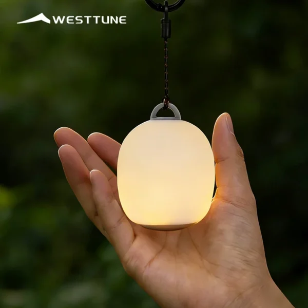 Silicone camping lantern mini light glowing softly, small enough to hold in one hand