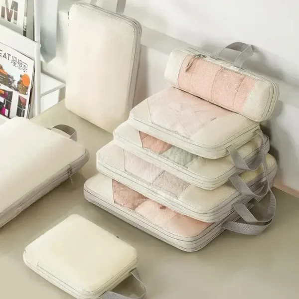 Metal zipper packing cubes 5 piece set in gray with mesh fronts arranged beside a suitcase
