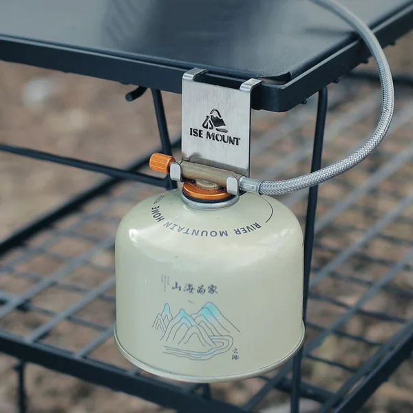 Steel gas canister hook hanging a stove fuel tank from the edge of a camping table
