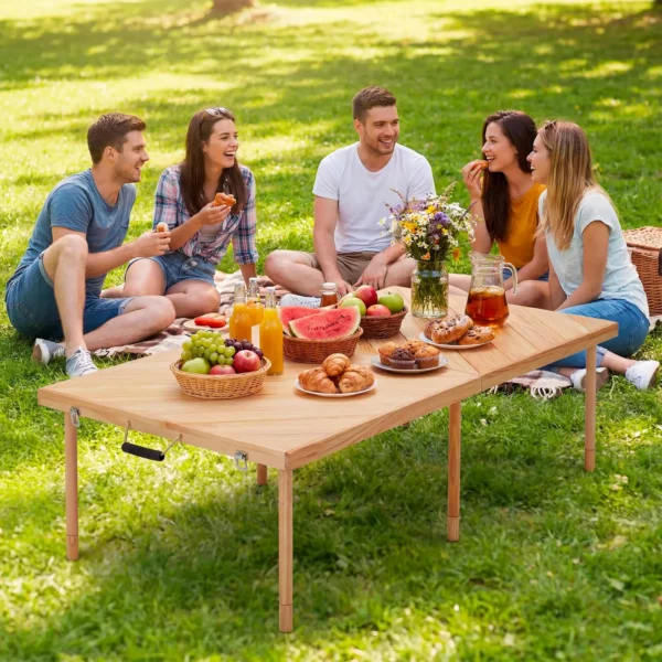 Solid wood picnic table folded open on a beach blanket with snacks and drinks set out