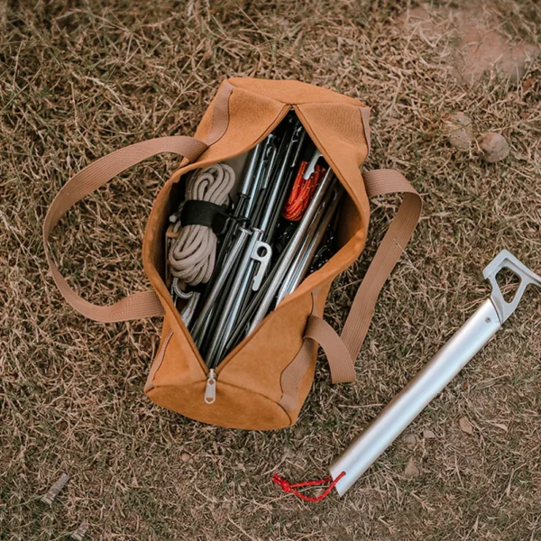 Canvas tent peg holder bag cylinder with woven handle, filled with steel tent stakes and a hammer