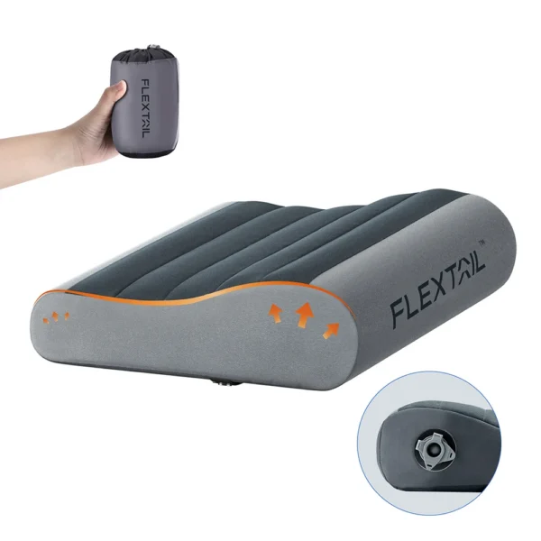 Grey washable inflatable camping pillow with an ergonomic curved shape resting on a sleeping pad
