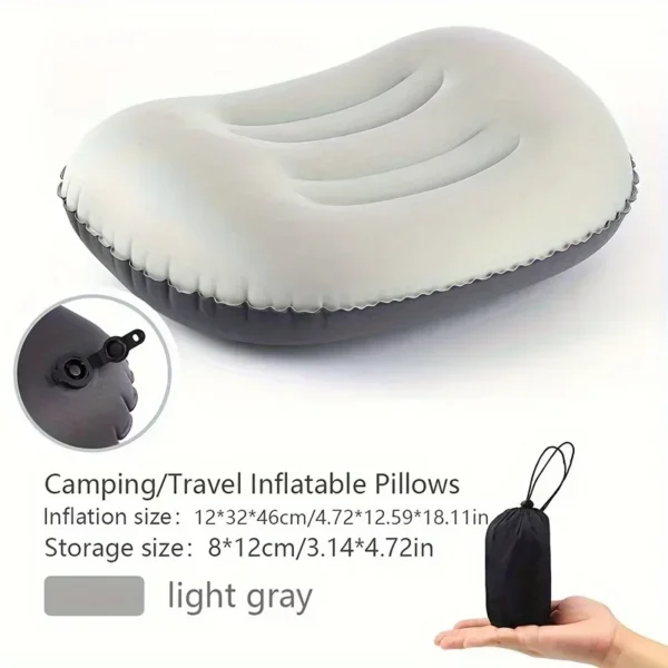 Compressible inflatable pillow in green beside its small carry pouch on a camping mat