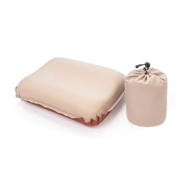 Grey green self inflating travel pillow with memory foam core resting on a backpack at a campsite