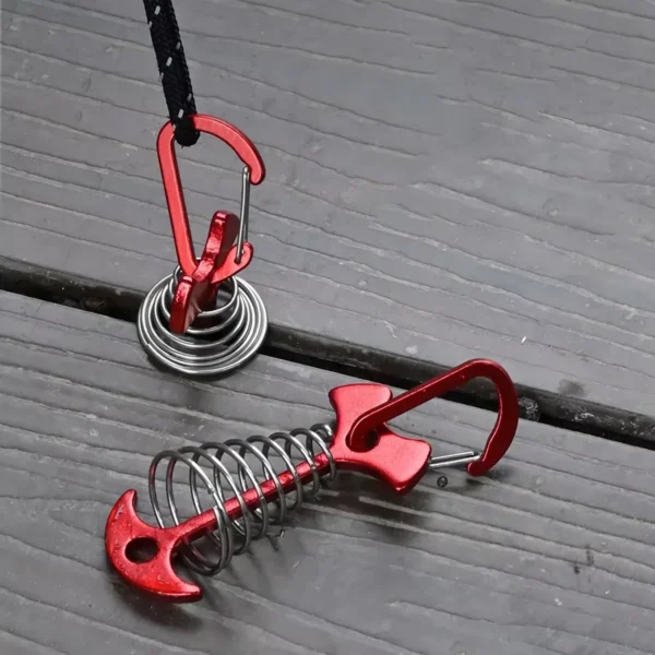 Five fish bone tent pegs in stainless steel with rope buckles fixed to a wooden camping deck