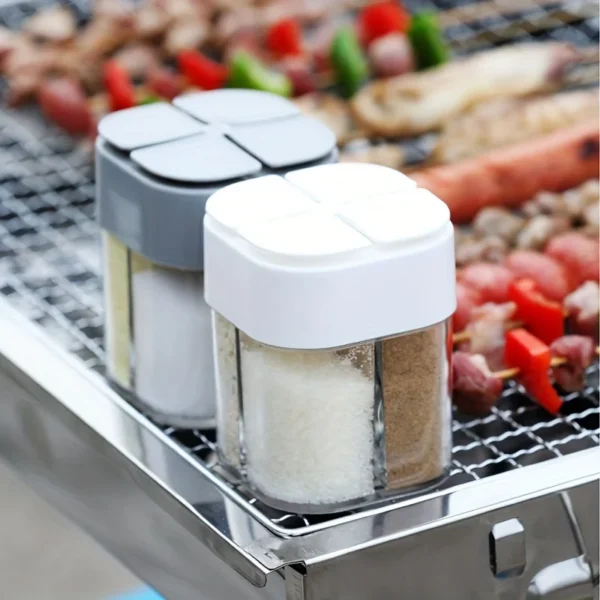 Grey 4 in 1 camping spice shaker with shaker lid on a camp table beside cooking gear