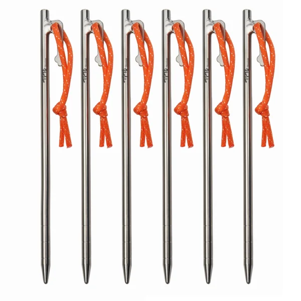 Titanium alloy tent pegs in several lengths laid out beside a family camping tent